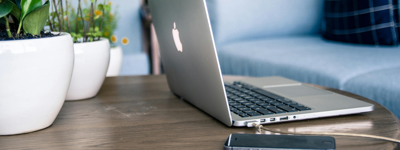 Laptop und Handy auf einem Couchtisch