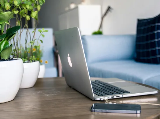 Laptop und Handy auf einem Couchtisch
