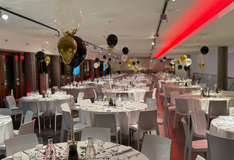 Eventlocation mit runden Tische und festlicher Weihnachtsdekoration mit Ballons und Konfetti